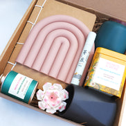 Collection of decorative items including candles, a notebook, and a tea set in a ritual wellness box.