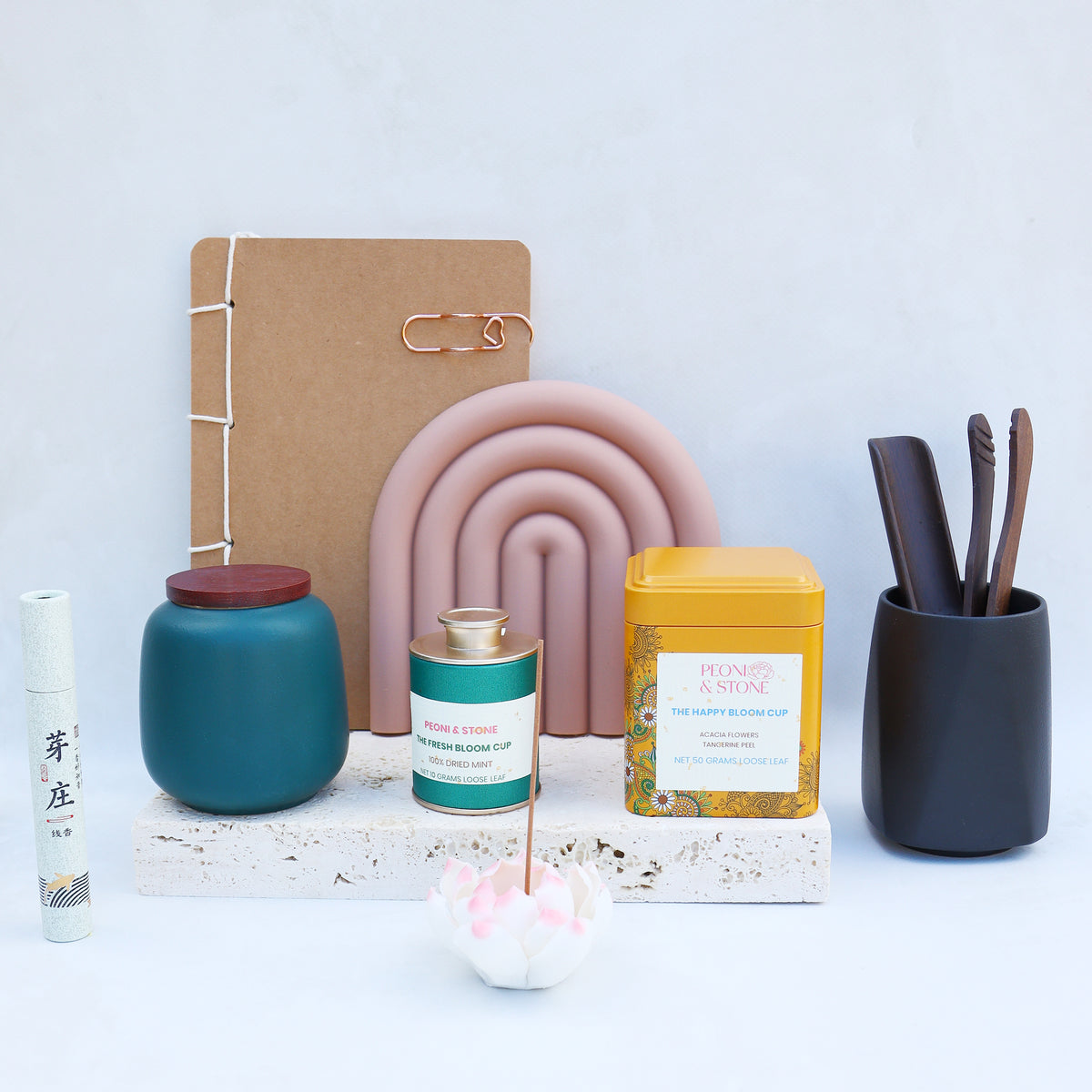 Collection of decorative items including a notebook, candles, and a holder on a light blue background