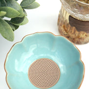 Turquoise ceramic tea strainer bowl with gold rim and perforated base for loose leaf tea