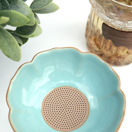 Turquoise ceramic tea strainer bowl with gold rim and perforated base for loose leaf tea