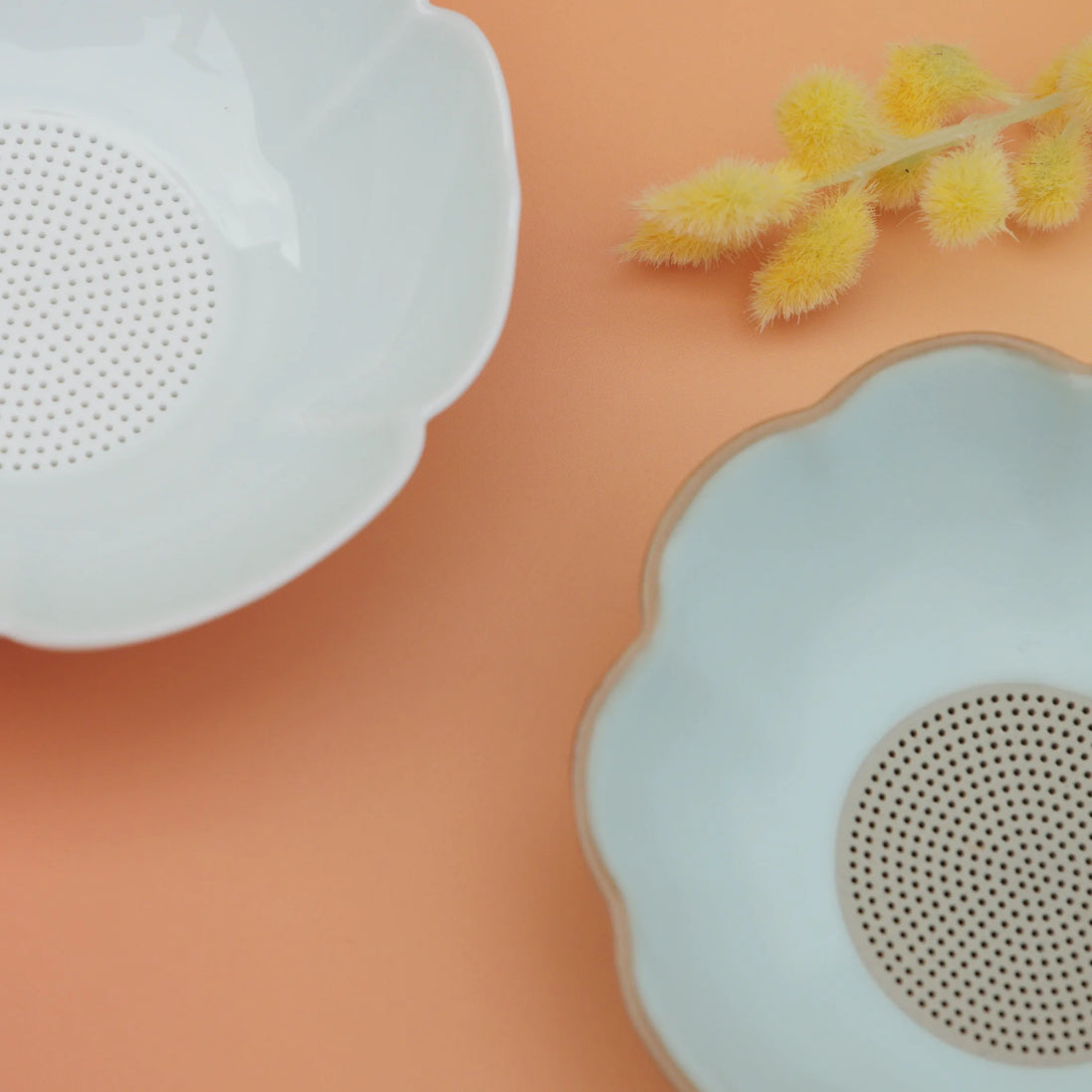 Cloud-shaped tea strainers in white and sage green with perforated centres on peach background
