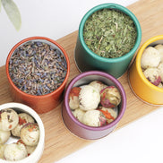 Colourful travel tea tins with loose leaf lavender, peppermint and herbal blends on bamboo board