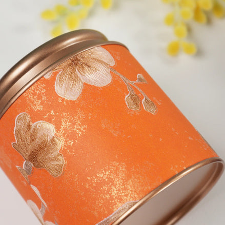 Orange floral tin candle with rose gold lid and gold botanical print detail