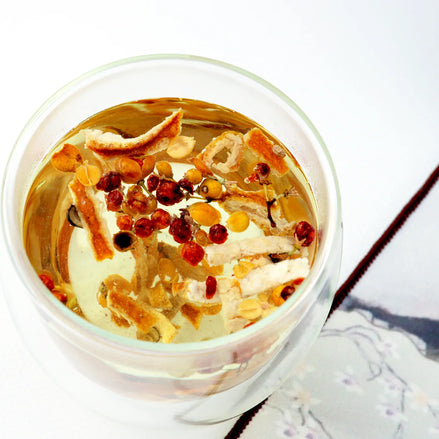Herbal tea in glass cup with citrus peel and red berries overhead view