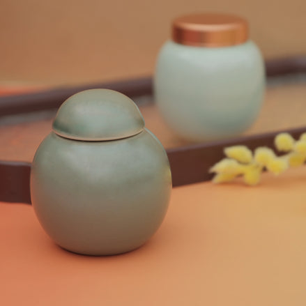 Jade green ceramic storage jar with dome lid on warm neutral surface