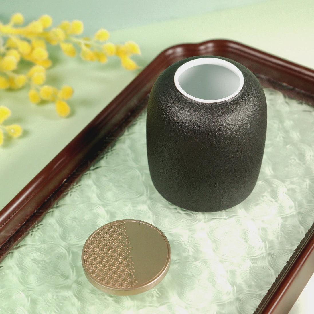 Kin jade green ceramic travel jar with white interior on decorative tray