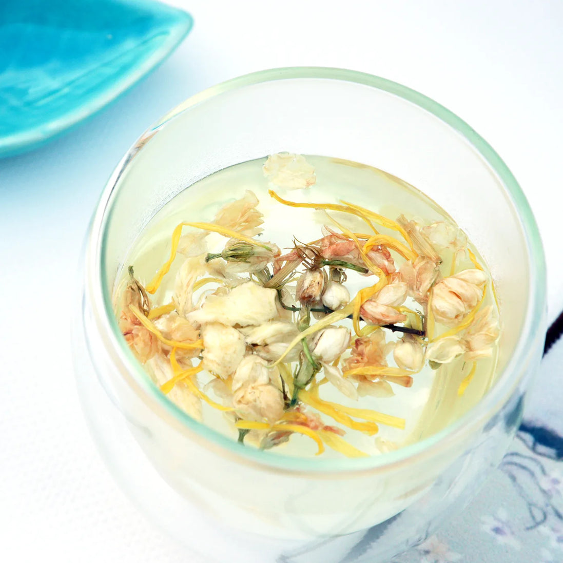 Loose leaf herbal tea blend with chamomile and calendula petals in glass cup