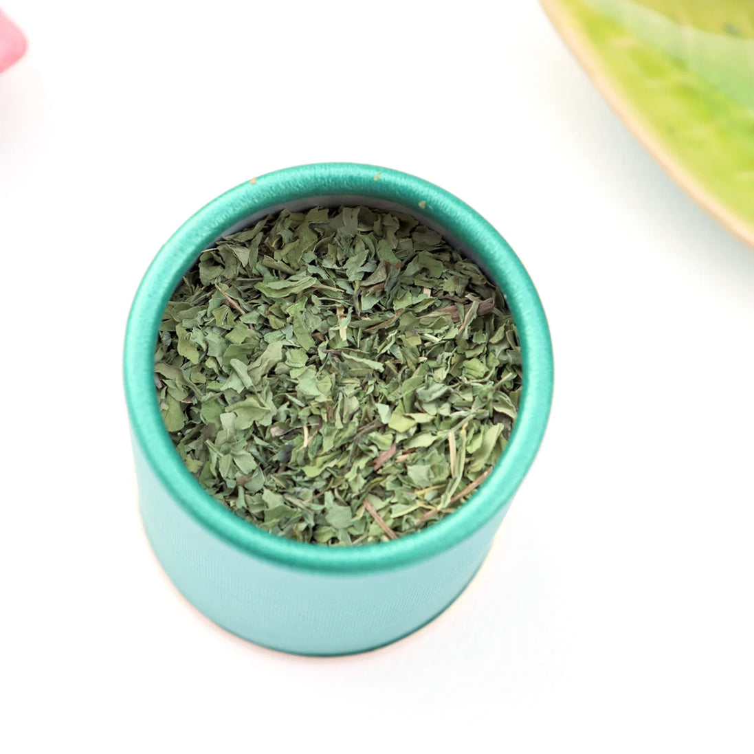 Loose leaf peppermint tea in turquoise storage container top view