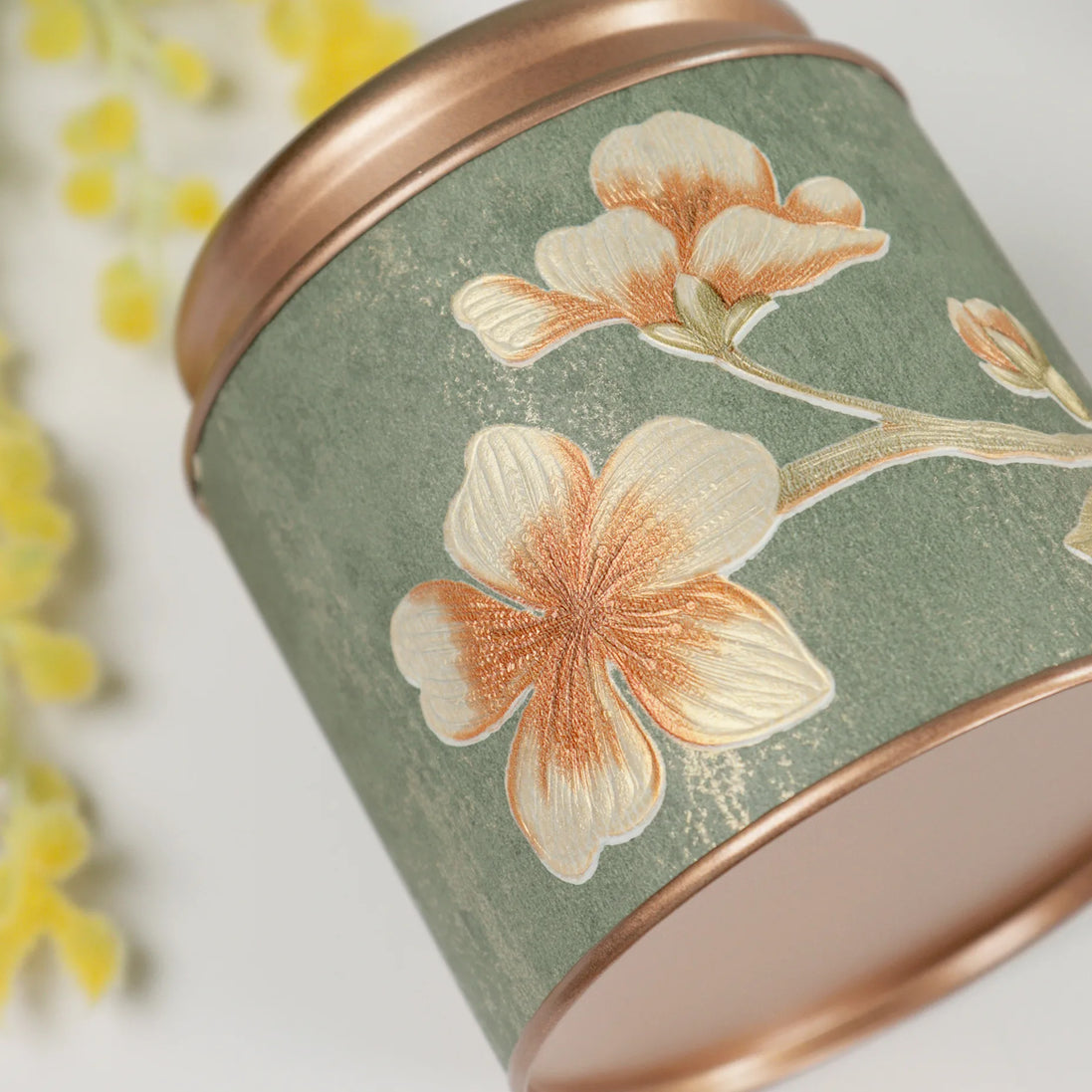 Sage green Manifestation Bloom candle with copper floral embroidery detail and rose gold lid