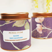 Purple tin candle with gold leaf botanical pattern and copper lid showing sandalwood, sage, and lavender blend