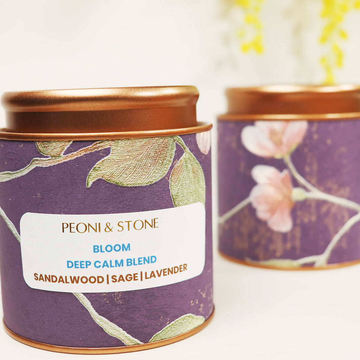 Purple tin candle with gold leaf botanical pattern and copper lid showing sandalwood, sage, and lavender blend