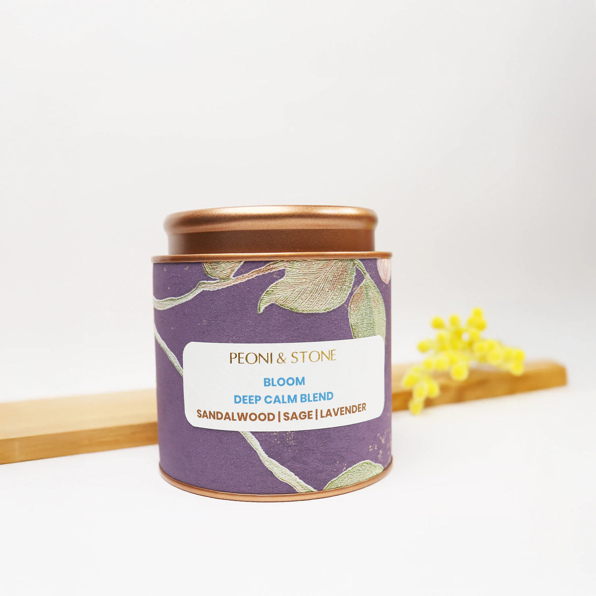 Purple botanical tin candle with copper lid featuring sandalwood, sage and lavender blend on wooden surface