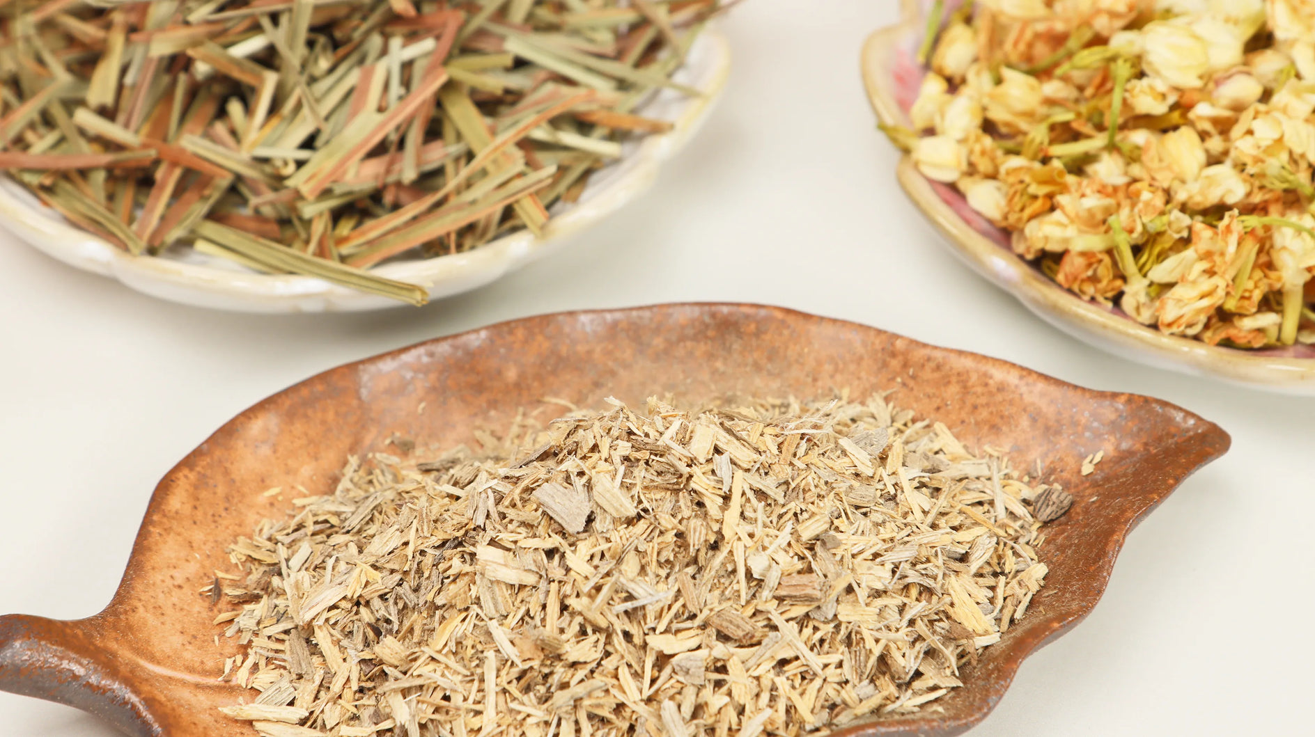 Dried agarwood chips with lemongrass and jasmine displayed on rustic wooden leaf-shaped dish