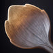 Handcrafted ceramic leaf-shaped burner with textured beige and gray organic glazing on black background
