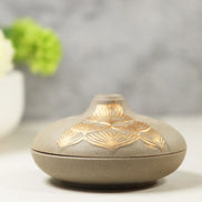 Grey ceramic incense burner with gold lotus petal patterns on rounded dome lid and matching base
