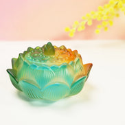 Turquoise and orange ombre glass lotus flower burner with detailed petals and textured center on white surface