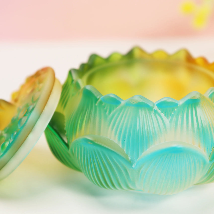 Turquoise and yellow ombre glass lotus burner with detailed petal edges on white surface