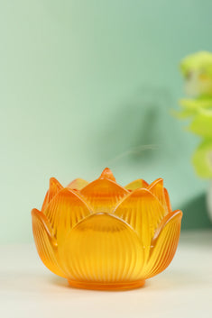 Amber glass lotus-shaped incense burner with layered petal design on soft green background