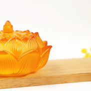 Amber translucent glass lotus flower incense burner with detailed petal engravings on wooden surface
