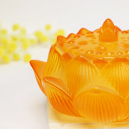 Amber translucent glass lotus flower incense burner with carved petals and perforated lid on white background