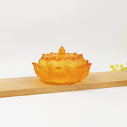 Amber translucent glass lotus flower incense burner with detailed petals and decorative lid on wooden surface
