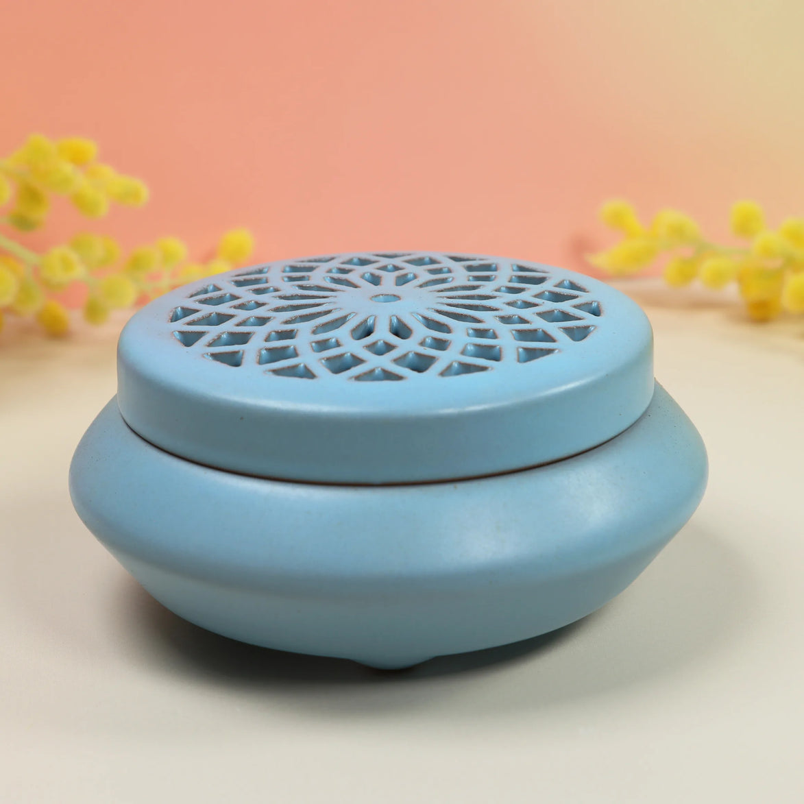 Blue ceramic incense burner with geometric lattice lid and rounded base on neutral background