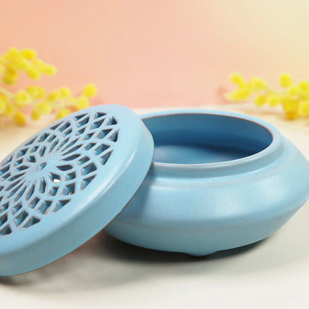Powder blue ceramic incense burner with decorative lattice lid sitting open on neutral background