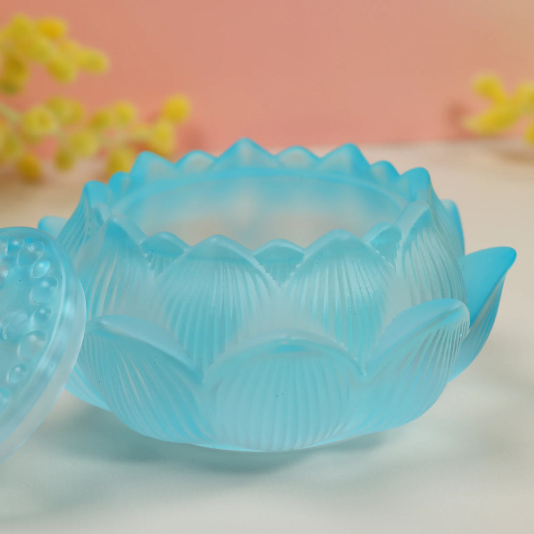 Frosted blue glass lotus flower incense burner with scalloped petal edges on neutral surface