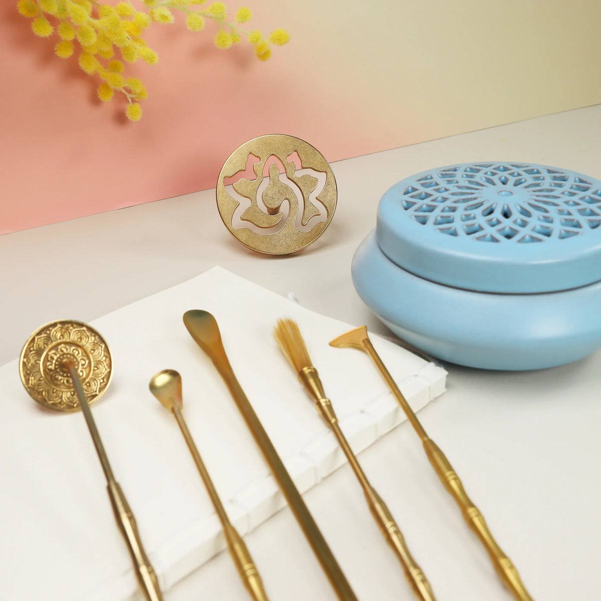 Blue lattice ceramic incense burner with gold brass tools and lotus seal mold on white marble surface