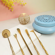 Blue ceramic incense burner with lattice pattern beside gold prosperity seal and brass sealing tools