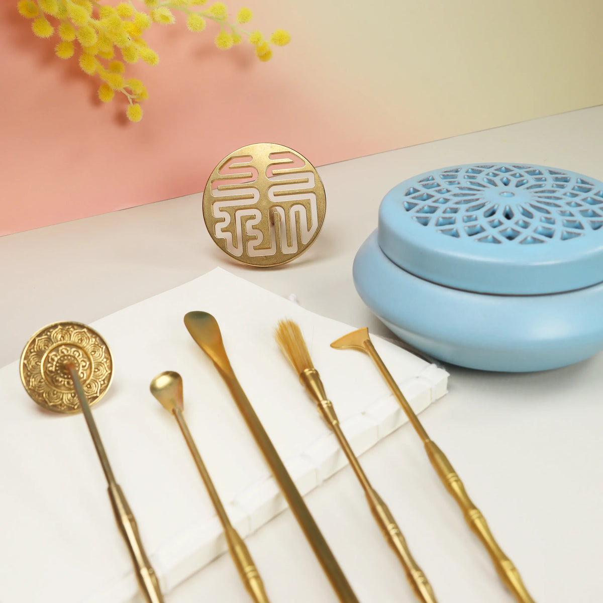 Blue ceramic incense burner with lattice pattern beside gold prosperity seal and brass sealing tools
