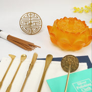 Amber glass lotus-shaped incense holder with double happiness seal, brass tools, and wooden incense sticks