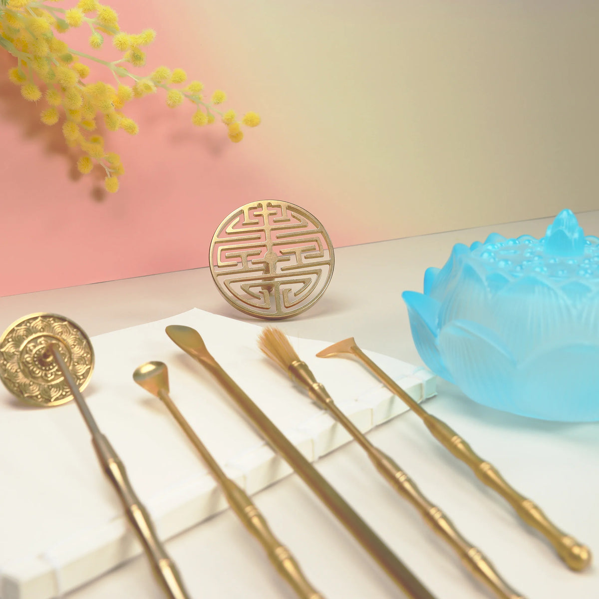 Dawn blue ombre glass lotus bowl with brass seal tools and concentric circle mold on white surface
