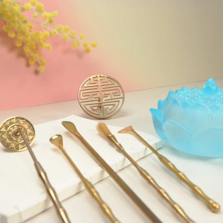 Dawn blue ombre glass lotus bowl with brass seal tools and concentric circle mold on white surface