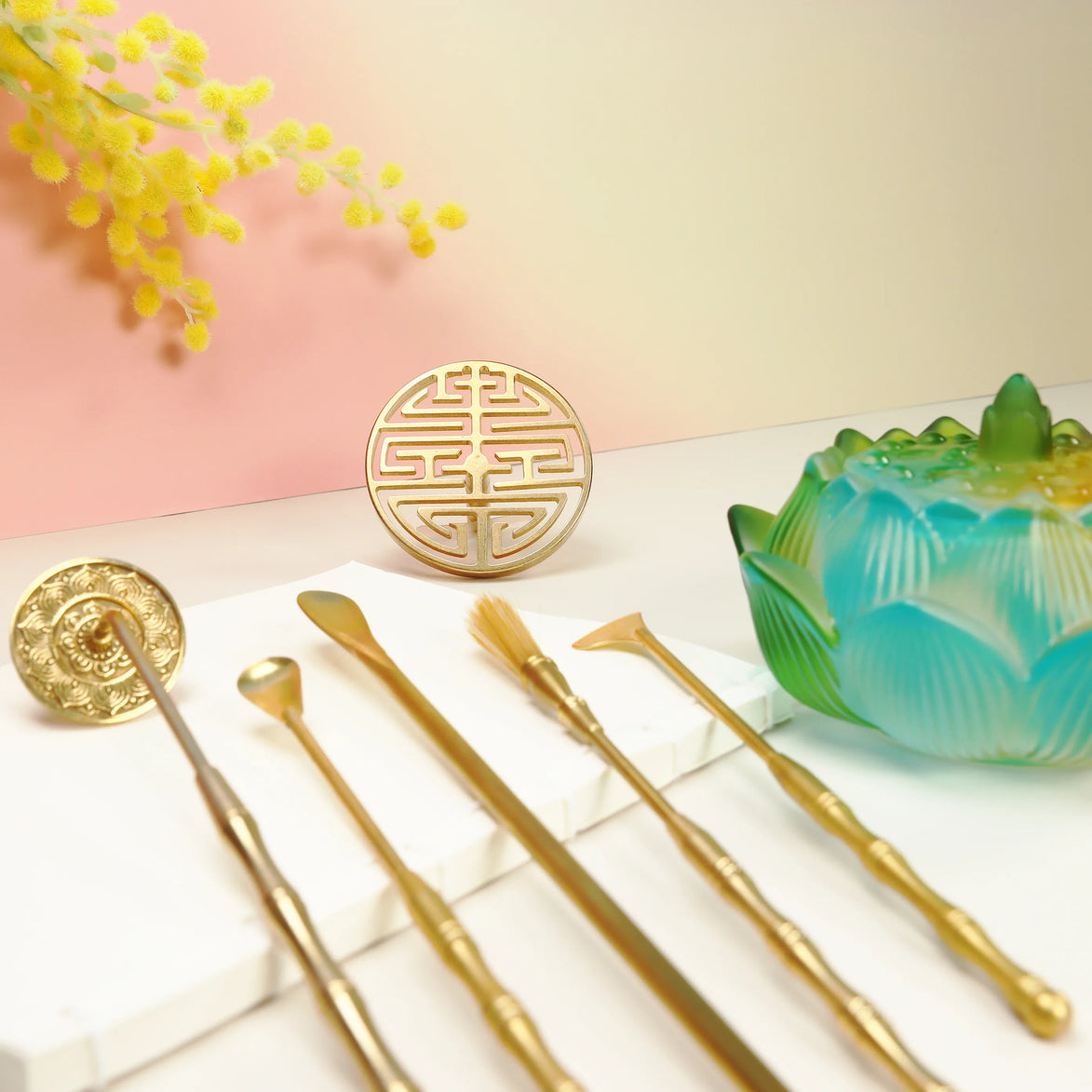 Three ombre glass lotus incense burners in blue, orange, and turquoise displayed on wooden board with flowers