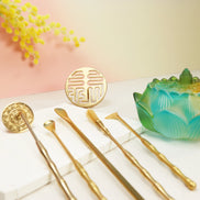 Brass prosperity seal and golden tea tools with dawn ombre glass lotus container on white marble