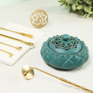 Turquoise ceramic incense burner with ornate cutout design alongside gold brass sealing tools and white mold