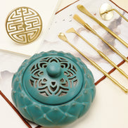 Turquoise ceramic incense burner with ornate cutouts alongside gold brass tools and double happiness seal mold