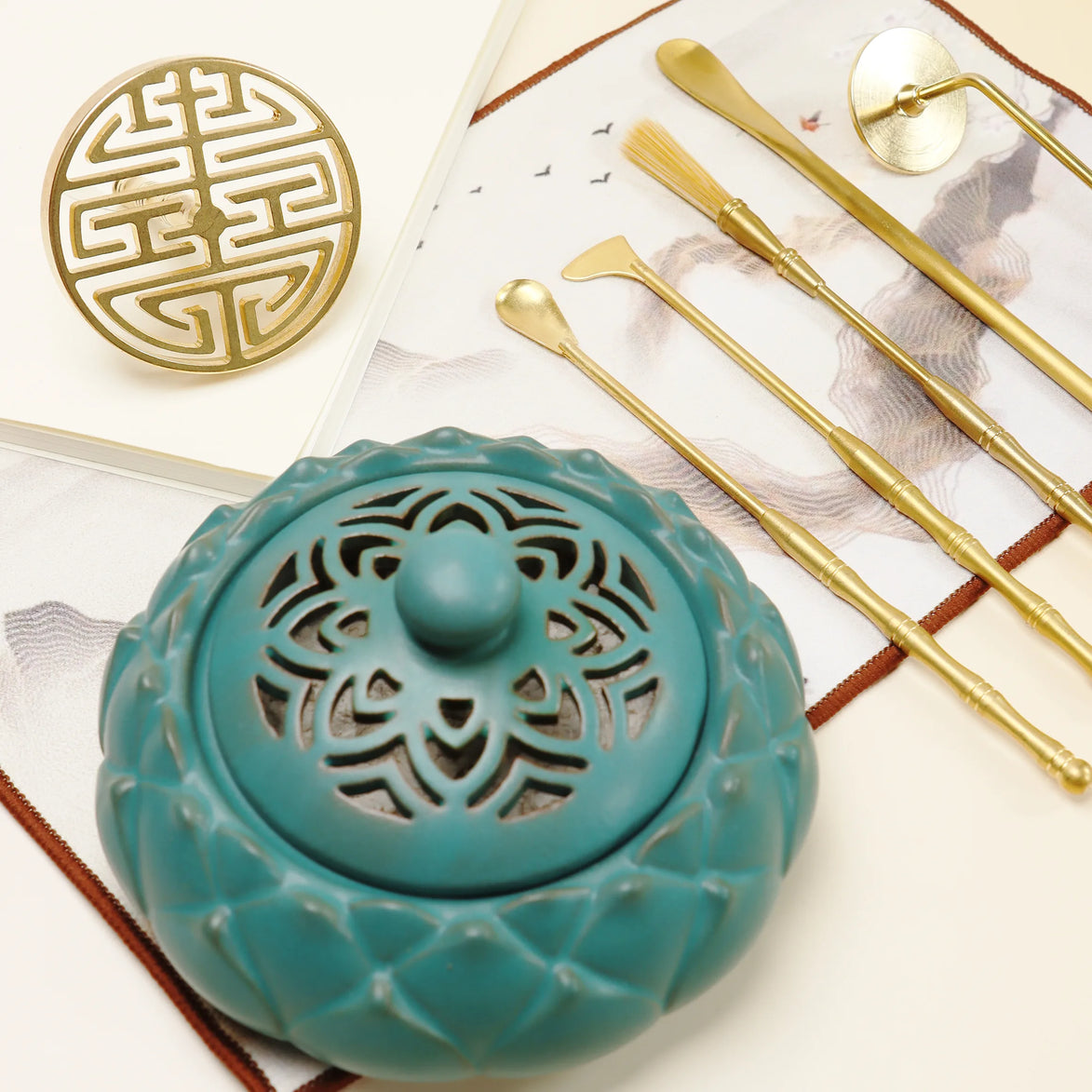 Turquoise ceramic incense burner with ornate cutouts alongside gold brass tools and double happiness seal mold