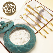 Turquoise lotus ceramic bowl with white powder and gold brass incense sealing tools arranged on textured surface