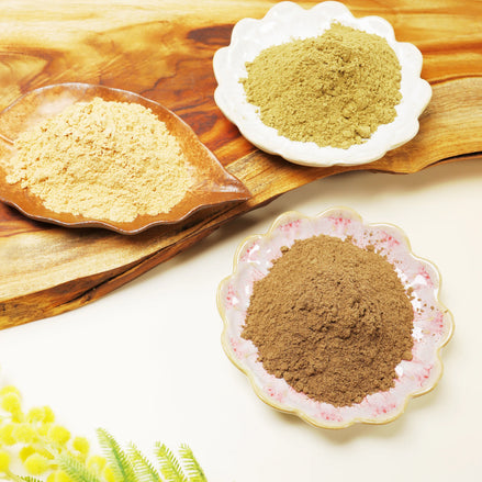 Three decorative bowls containing different colored natural incense powders on wooden background