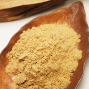 Golden powder incense blend in wooden spoon with natural wood surface background