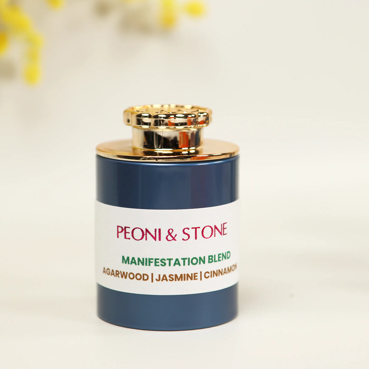Navy blue glass incense jar with gold cap and white label reading Peoni & Stone Manifestation Blend