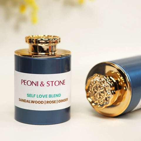 Navy blue aromatherapy bottle with ornate gold crown cap, labeled Self Love Blend with sandalwood, rose and ginger