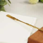 Elegant brass-handled brush with natural bristles lying on white paper, featuring golden metallic finish
