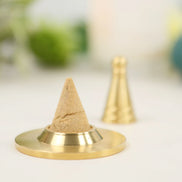 Copper cone-shaped incense mold on golden base with formed incense cone, second cone visible in background