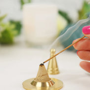 Gold-toned copper incense cone maker with powder blend on brass base, hand lighting with incense stick