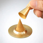 Hand holding gold copper cone maker pouring powder onto circular base forming cone shape