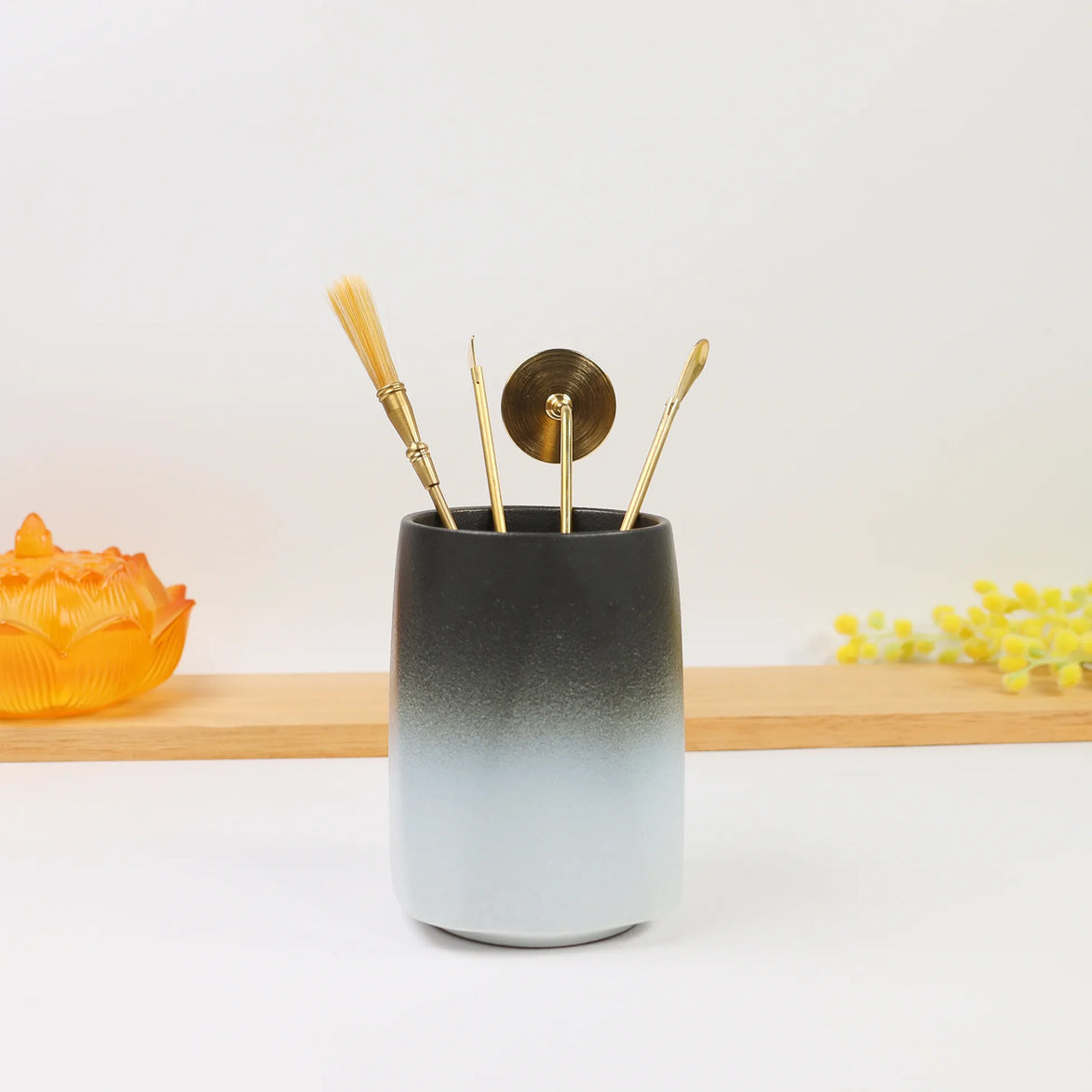 Charcoal to white ombré ceramic holder with brass sealing tools and candle snuffer displayed on wooden shelf