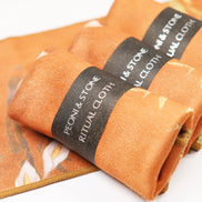 Orange suede ritual cloth with fleece backing rolled and banded with black Peoni & Stone label